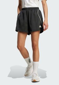 Svarte treningsshorts med hvite sidestreker, elastisk midje, sidelommer og lett stoff, kombinert med hvite sokker og joggesko.