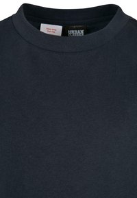 Tamsiai jūrinės mėlynos spalvos crew neck tipo marškinėliai su matoma Urban Classics prekės ženklo etikete ir gaisrinės saugos įspėjimo žyme ant vidinės apykaklės.