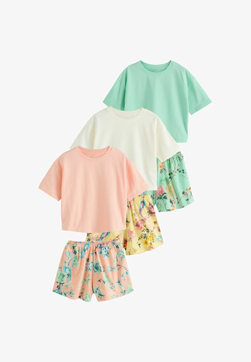 Trois hauts à manches courtes en vert pastel, crème et pêche, assortis à des shorts imprimés floraux aux couleurs coordonnées.