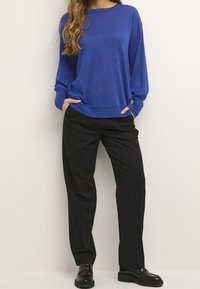 Maglione a maniche lunghe blu in maglia con vestibilità comoda, abbinato a pantaloni neri su misura e scarpe nere stringate.