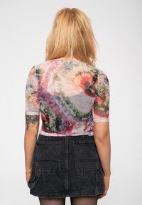 Sheer, tie-dye top featuring multicolored swirling patterns in pink, green, and orange. Short sleeves and round neckline.