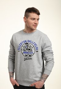 Grijze sweatshirt met lange mouwen. Bevat blauwe tekst "ALLERTON BALLFIELDS" en een afbeelding van een figuur, met "BRONX CITY" en "Park Fields" daaronder.