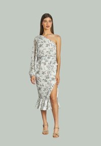 Weißes Blumenkleid mit einem langen Ärmel, Rüschensaum und seitlichem Schlitz. Es verfügt über einen Blumenmuster mit grünen Blättern und hellrosa Blumen.