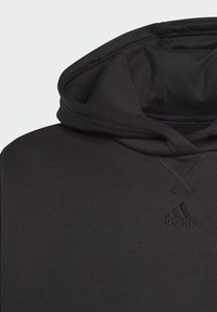 Felpa nera con cappuccio in stile hoodie, caratterizzata da una tasca a marsupio, cappuccio con drawstring e tessuto testurizzato. Presenta un logo sottile sul petto e una vestibilità rilassata.