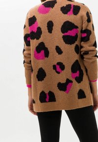 Brun stickad kofta med svarta och rosa leopardfläckar, med en avslappnad passform, ribbade manschetter och en enfärgad rosa accent vid ärmkanterna.