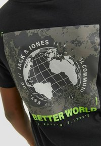 Svart t-shirt med en grå jordglob grafik, texten "JACK & JONES" och grön "BETTER WORLD" detalj nära fållen.