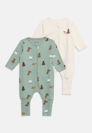 Deux grenouillères pour bébé, une verte avec divers motifs de chiens, et une crème avec un petit motif de couple de chiens sur la poitrine, toutes deux avec fermeture éclair devant.
