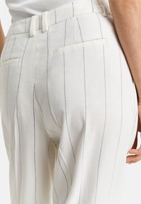 Weiße gestreifte Hose mit hellgrauen vertikalen Linien, flachem Bund, zwei Gesäßtaschen und einer leinenähnlichen Textur.