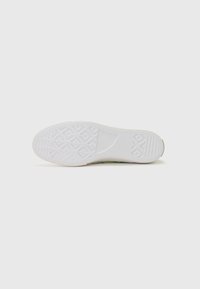 Talpa de sneaker albă cu un model texturat de priză, având o formă rotunjită și un design minimalist, cu accente verde deschis aproape de margini.