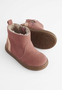 Botine din suede roz, cu căptușeală din blană sintetică, fermoar lateral și talpă din cauciuc. Prezintă dungi verticale într-o nuanță mai deschisă pe lateral.