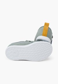 Scarpe di tela verdi con un supporto per il tallone in suede giallo e suola in gomma bianca. Presentano un motivo di grip testurizzato sulla suola per una maggiore aderenza.