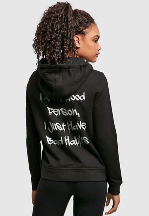 Schwarzer Baumwollhoodie mit Kapuze und Schnürung, eng anliegende Bündchen und weißem Graffiti-Stil-Text auf dem Rücken, der lautet: "Ich bin eine gute Person, ich habe nur schlechte Gewohnheiten."