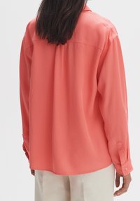 Korallenrotes Hemd mit langen Ärmeln, Knopfmanschetten und einer glatten Textur. Mit einem Passe-Detail am Rücken und einer lockeren Passform.