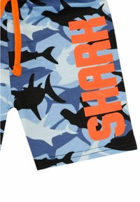 Zwemshorts van lichtblauwe stof met zwarte haai-silhouetten en oranje "SHARK" tekst. Voorzien van een verstelbare oranje trekkoord.