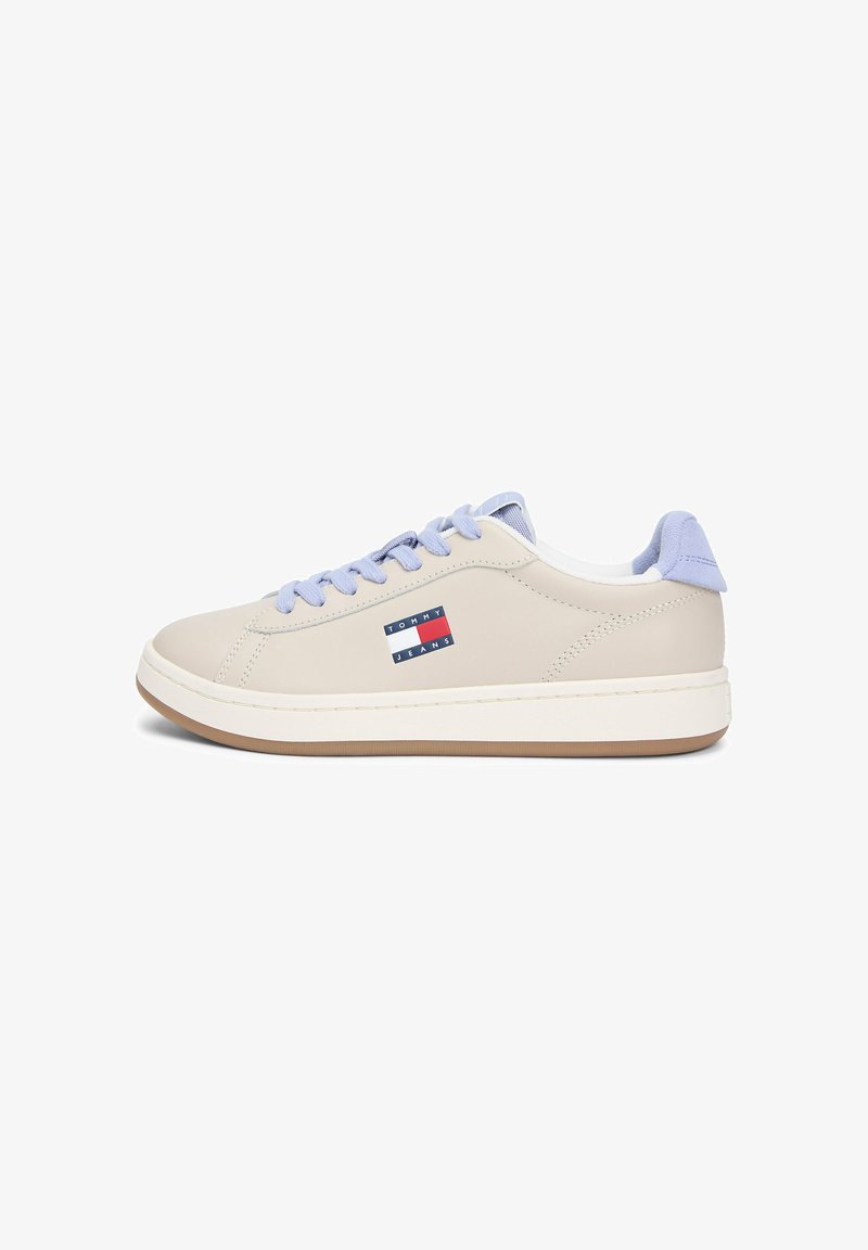 Baskets basses beige avec lacets violet clair et languette au talon, semelle blanche et logo Tommy Jeans sur le côté.