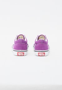 Lila mockask slip-on skor med vita sulor, med svart trim och en röd Vans-logotyp på hälen. Sömnadsdetaljer synliga på ovandelen.