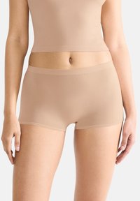 Ljusbruna boyshorts gjorda av mjukt material med en platt midja. Tätt sittande design med sömlösa kanter för komfort och minimala synliga linjer.