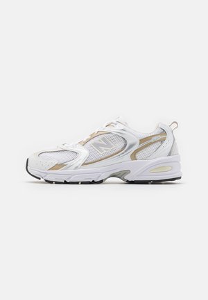 White and beige New Balance 530 sneaker with mesh and leather upper, lace-up design, and thick cushioned sole shown in side view on white background.