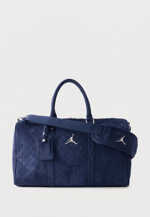 Tmavomodrá duffel taška s textúrovaným vzorom "23", dvojitými rukoväťami, odnímateľným polstrovaným ramenným popruhom a strieborným logom Jumpman vpredu.