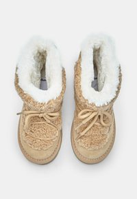 Hnedé členkové topánky s kožušinovým podšívaním, textúrovaným vonkajškom a šnurovaním. Mäkký interiér a zaoblený tvar špičky. Gumová podrážka pre lepšiu priľnavosť.