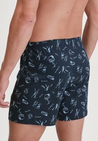 Marineblauwe boxershorts met verschillende ski- en kabelbaanafbeeldingen in lichtgrijs en rood. Voorzien van een elastische tailleband voor comfort.