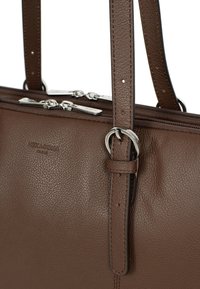 Bruine leren handtas met een gestructureerde afwerking, dubbele ritsvakken, verstelbare bandjes en zilverkleurige metalen accenten.