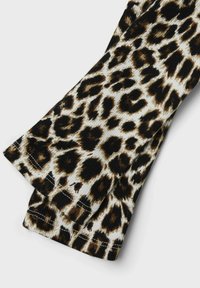 Tkanina w wzór panterki o żebrowanej teksturze, z paletą kolorów kremowego, czarnego i brązowego. Widoczne surowe krawędzie szwów.