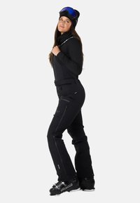 Sort skitøj med justerbare stropper, slim fit, sidelommer og forstærkede manchetter. Inkluderer sorte skistøvler med metallisk accent.