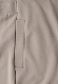 Vaalean beige kangas, jossa on sileä pinta, ja siinä on suorakaiteen muotoinen paikka sekä hienovaraiset ompelusat.