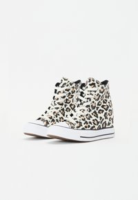 Høye sneakers med et beige leopardmønster, hvite snører og gummisåler. Svarte detaljer og en logo på den ytre siden.