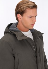 Grå hættejakke med en struktureret grå foring, frontlynlås og trykknapper, der har et enkelt, strømlinet design.