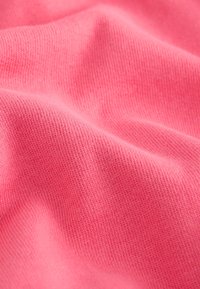 Weicher, glatter rosa Strickstoff mit sanften Falten und feiner, gleichmäßiger Textur aus der Nähe.