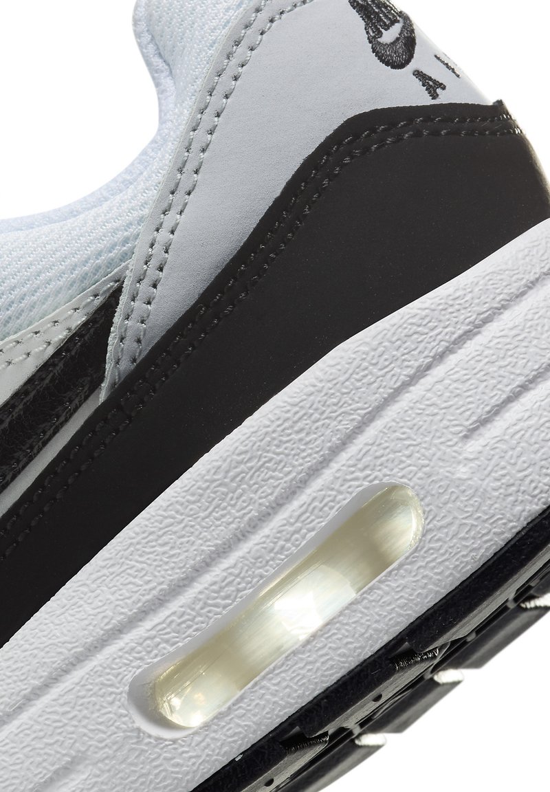Sneaker met een lichtblauwe bovenkant en zwarte accenten, een gestructureerde witte tussenzool en een zichtbare luchtkusseneenheid. Genaaid detail aanwezig.