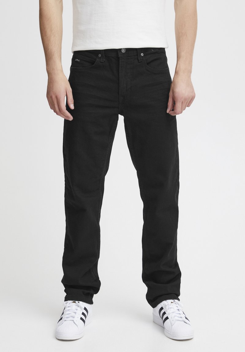 Black denim jeans with a straight fit, featuring a classic five-pocket design and subtle stitching. Worn with white sneakers.