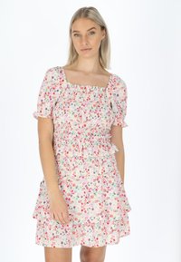 Kleid mit Blumenmuster, das über einen quadratischen Ausschnitt, kurze Puffärmel und einen Rüschensaum verfügt. Die Farben umfassen Rosa, Rot, Grün und Lila auf einem hellen Hintergrund.