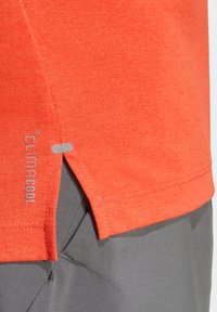 Camiseta deportiva ligera en color naranja con una ventilación lateral. Marca "ClimaCool" en gris en el dobladillo. Textura suave con un diseño transpirable.