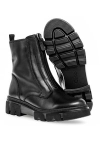 Bottines en cuir noir avec une fermeture éclair sur le côté, semelle en caoutchouc épaisse, motif de semelle texturé et détails de couture renforcée.