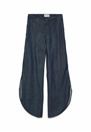 Tamne traper hlače širokih nogavica s zaobljenim prorezima na rubu s obje strane, prednji patentni zatvarač i oznaka na pojasu s natpisom AWARE.