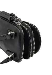 Czarna skórzana torba z trzema zamykanymi na zamek komorami, z dodatkami w srebrnym odcieniu i gładką teksturą. Dołączony krótki uchwyt.