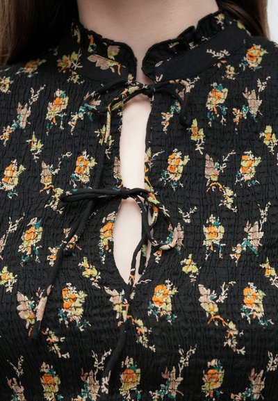 Μαύρη μπλούζα από ζαρωμένο ύφασμα με floral σχέδιο σε πορτοκαλί, κίτρινο και πράσινο. Διαθέτει γιακά με βολάν και άνοιγμα τύπου keyhole με κορδόνια.