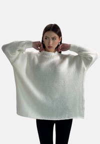 Maglione bianco oversized lavorato a maglia con un alto colletto a coste e spalle cadute. Tessuto testurizzato con una vestibilità ampia e maniche lunghe.