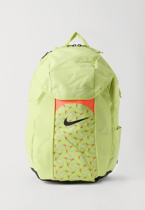 Mochila Nike verde-claro com o logótipo swoosh preto, bolso frontal com padrão geométrico, bolsos laterais e pega superior em fundo branco.
