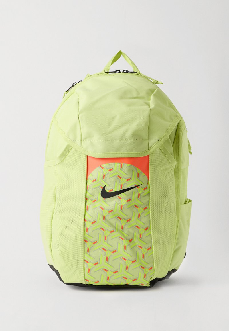Mochila Nike verde claro con el logotipo de swoosh negro, bolsillo frontal con patrón geométrico, bolsillos laterales y asa de transporte en la parte superior sobre un fondo blanco.