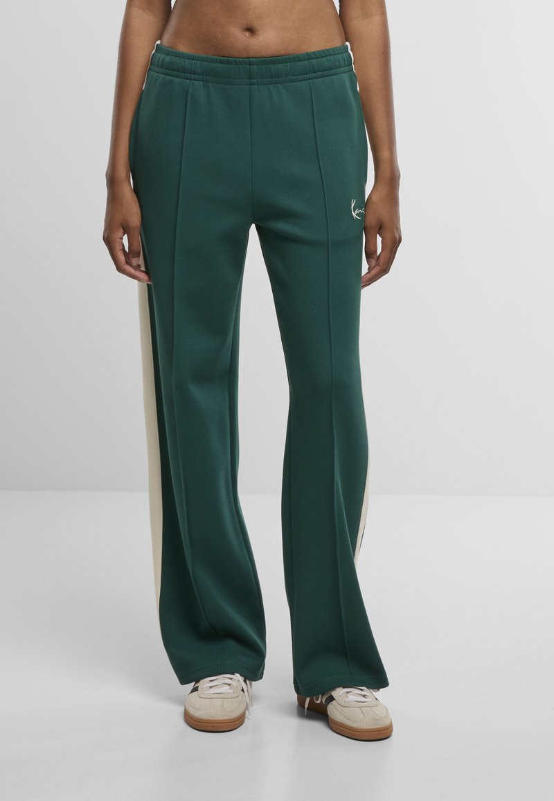 Groene sweatpants van zacht materiaal met lichtbeige zijstrepen, voorzien van een tailleband met trekkoord en een logo-accent aan de voorkant.