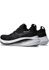 Baskets de sport noires avec une tige texturée, arborant des accents argentés et une semelle intermédiaire blanche, conçues pour l'amortissement et le soutien.