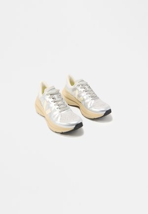 Paire de baskets à lacets argentées et beiges avec semelles épaisses, de la marque « Condor », présentées sur un fond blanc.