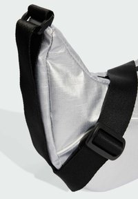 Borsa triangolare argentata con superficie testurizzata, tracolla nera regolabile e dettaglio in plastica con fibbia. Caratterizzata da un materiale liscio e lucido.