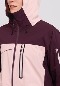 Purple and light pink waterproof jacket with a hood, featuring a front zipper and two zippered pockets, made of smooth, durable fabric.