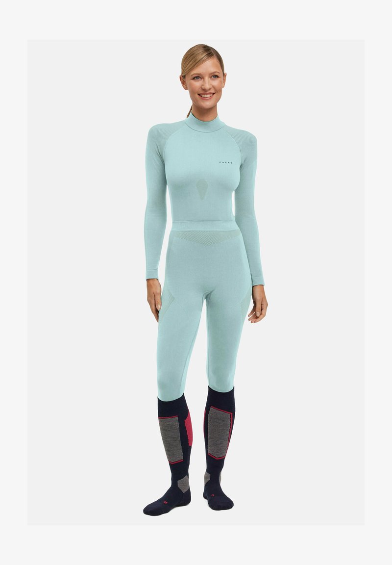 Tuta full-body azzurro chiaro con maniche lunghe, texture a coste e design senza cuciture. Abbinata a calze blu scuro con dettagli grigi e rossi.