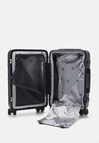 Crni kofer na kotačima s rajsnama, sivo unutrašnjost, mrežasti džep i podstava s logotipom. Otvoren i ravno položen, otkriva dva odvojena odjeljka.